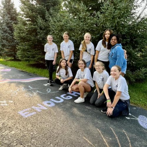 volunteers pose for picture next to chalk art